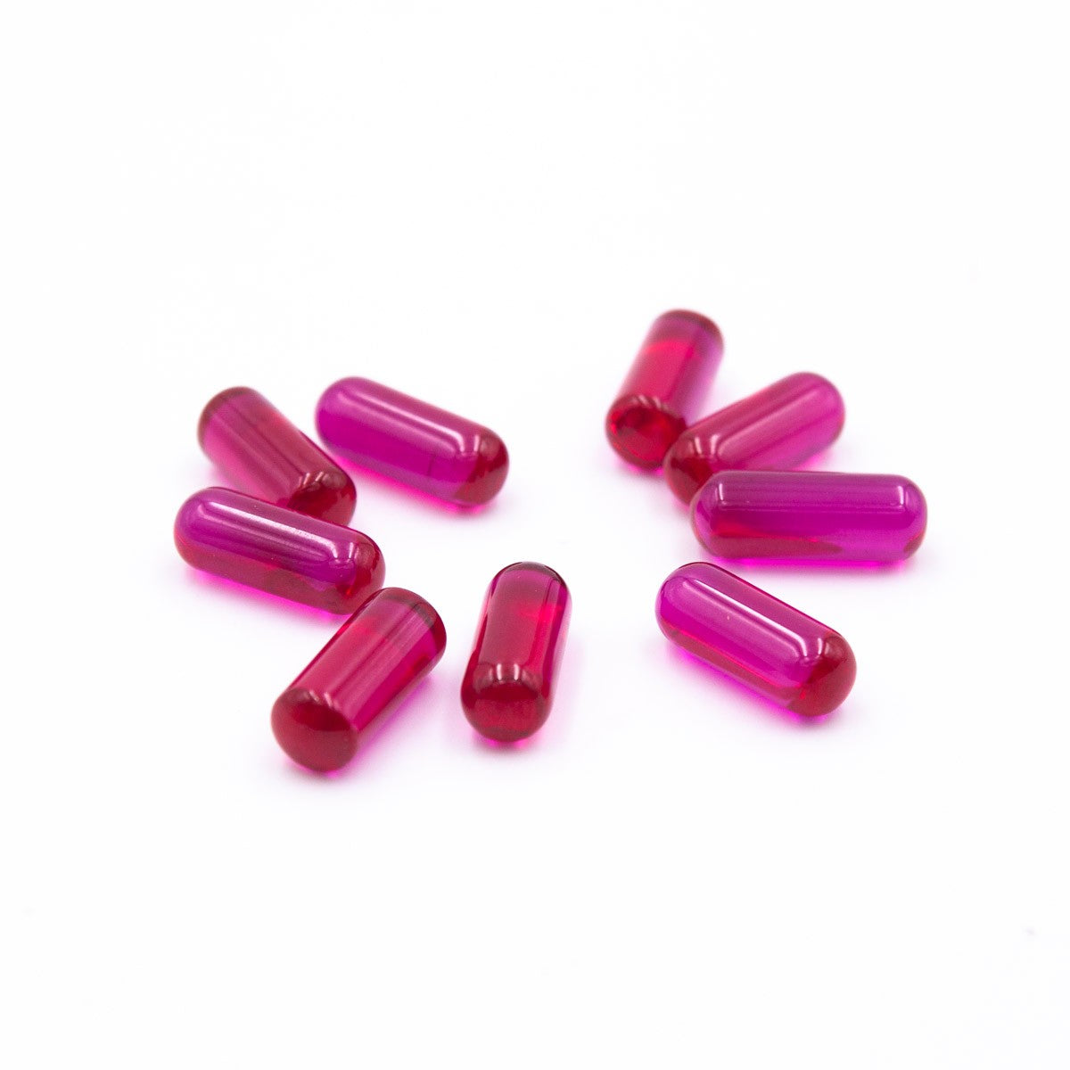 Overhead view of several 15mm Ruby Terp Pills scattered across a white surface, showcasing their smooth, rounded shape. Overhead view of several 15mm Ruby Terp Pills scattered across a white surface, showcasing their smooth, rounded shape.