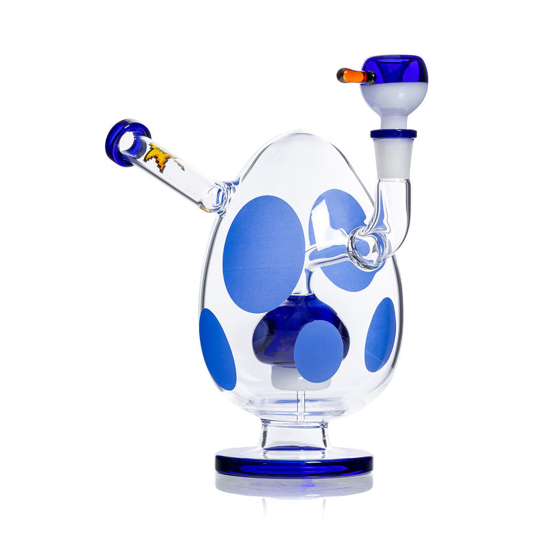 Front view of the Spotted Egg XL Bong, showcasing a clear glass piece with blue polka dots and a rounded base on a reflective surface. Front view of the Spotted Egg XL Bong, showcasing a clear glass piece with blue polka dots and a rounded base on a reflective surface.