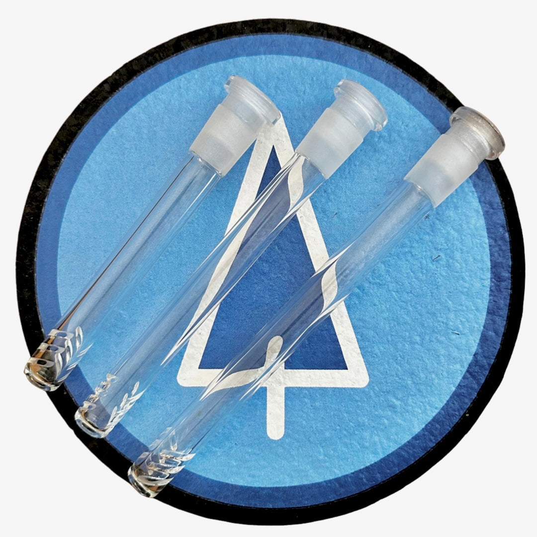 A close-up, angled view of the SnowTree Glass Downstem, showcasing its clear glass construction against a textured blue background. A close-up, angled view of the SnowTree Glass Downstem, showcasing its clear glass construction against a textured blue background.