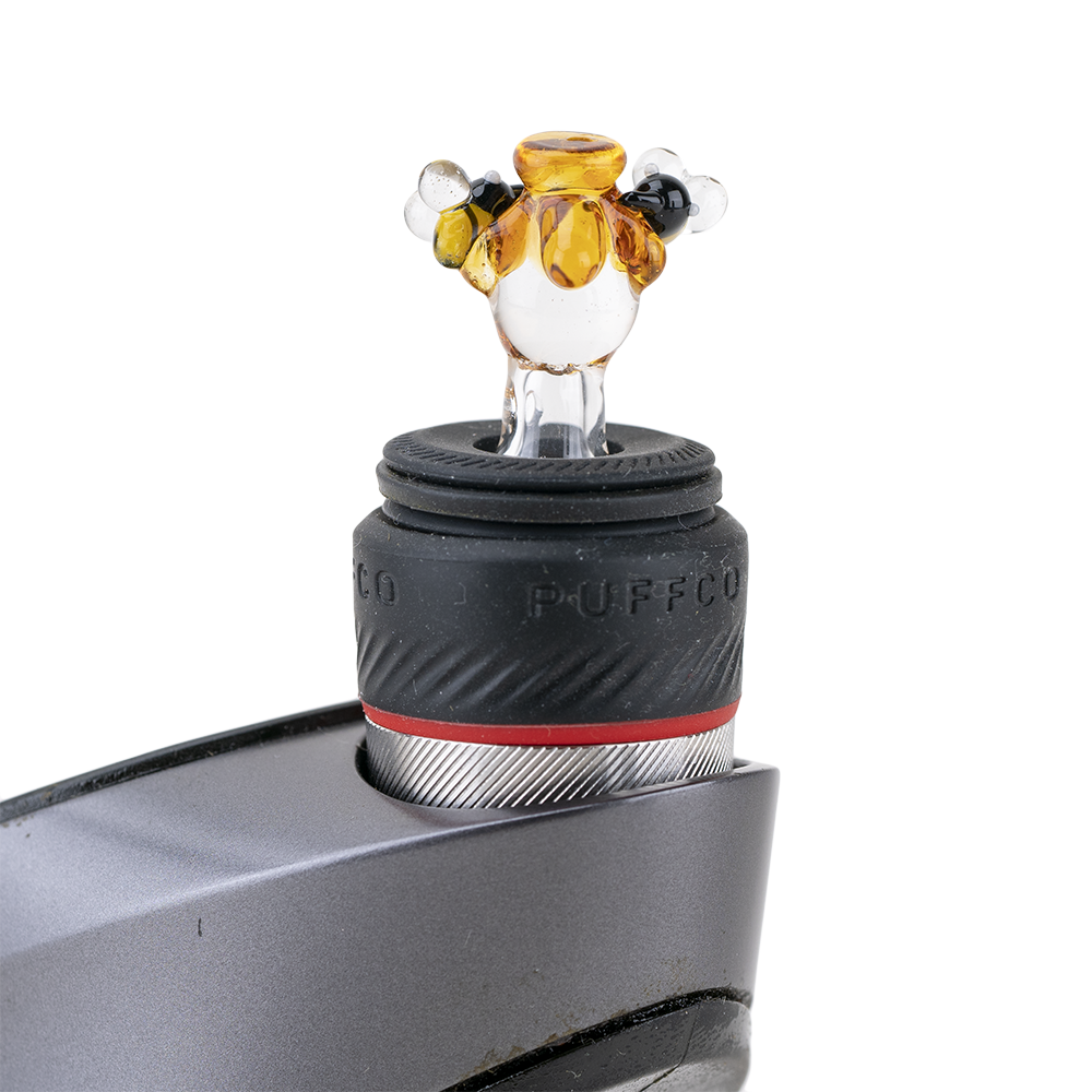 Close-up of the Beehive PuffCo Peak Pro Glass Ball Cap, showcasing its clear glass construction and rounded shape. Close-up of the Beehive PuffCo Peak Pro Glass Ball Cap, showcasing its clear glass construction and rounded shape.