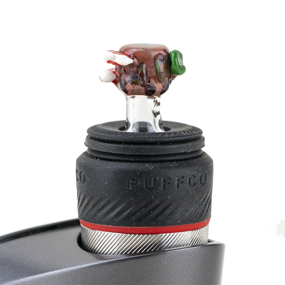 A close-up shot of the Hootie PuffCo Peak Pro Glass Ball Cap resting on a textured black surface, showing its rounded shape. A close-up shot of the Hootie PuffCo Peak Pro Glass Ball Cap resting on a textured black surface, showing its rounded shape.