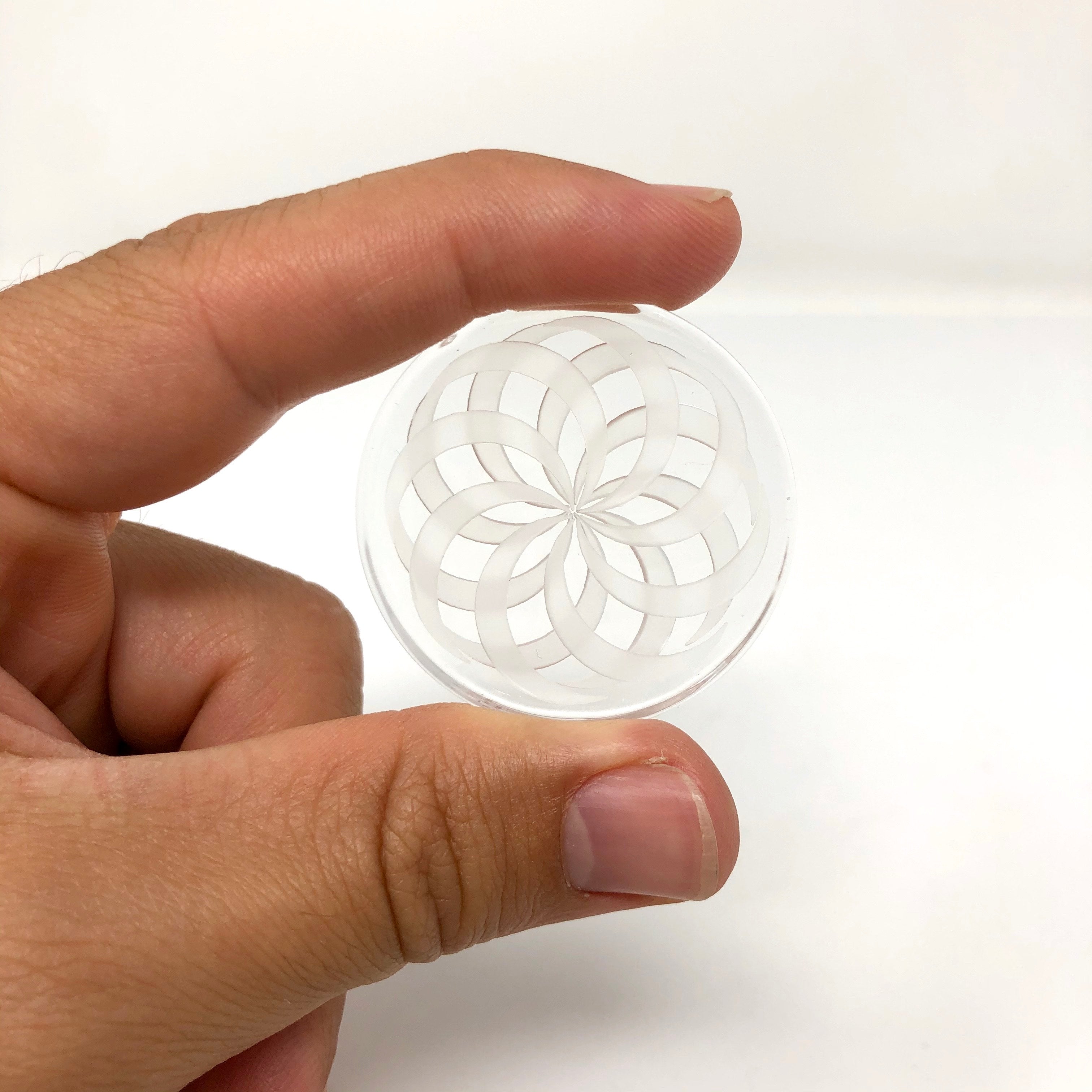 A hand holds the clear Disc Spinner Carb Cap, displaying its circular design and transparent material. A hand holds the clear Disc Spinner Carb Cap, displaying its circular design and transparent material.