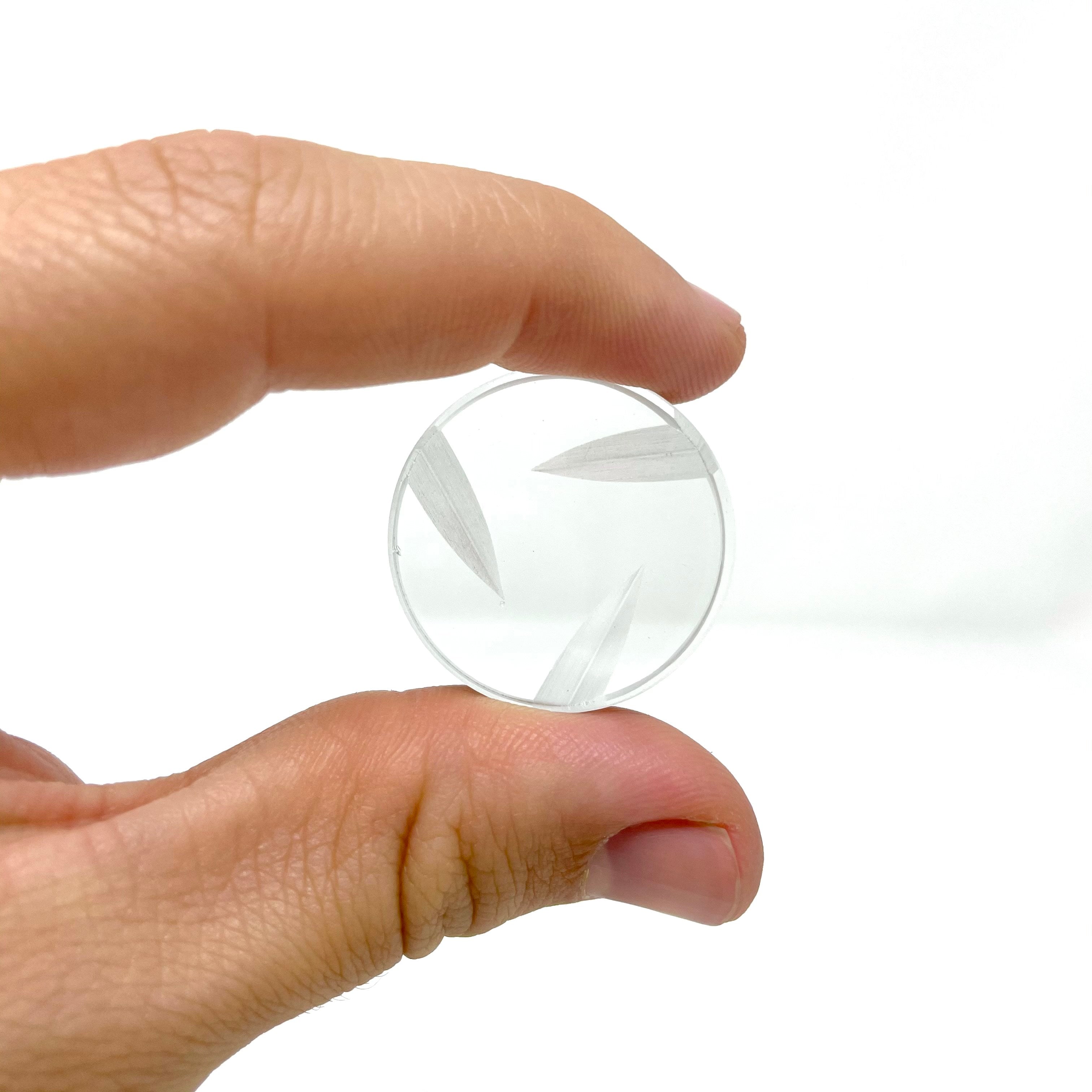 A close-up shows the Disc Spinner Carb Cap V2 held between fingertips, its transparent disc design visible against a bright background. A close-up shows the Disc Spinner Carb Cap V2 held between fingertips, its transparent disc design visible against a bright background.