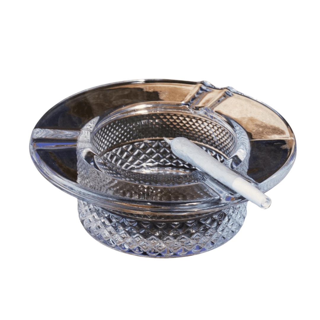 A close-up, angled view of the Twenties Collection Ashtray, displaying a cigarette resting within its patterned glass bowl. A close-up, angled view of the Twenties Collection Ashtray, displaying a cigarette resting within its patterned glass bowl.