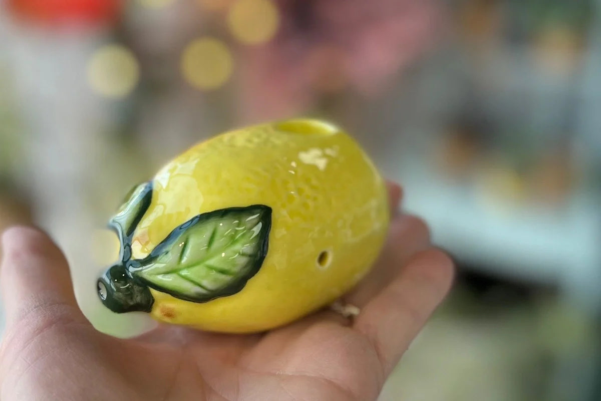 A close-up shot of the Lemon Pipe held in a hand, showcasing its detailed, curved design against a blurred background. A close-up shot of the Lemon Pipe held in a hand, showcasing its detailed, curved design against a blurred background.