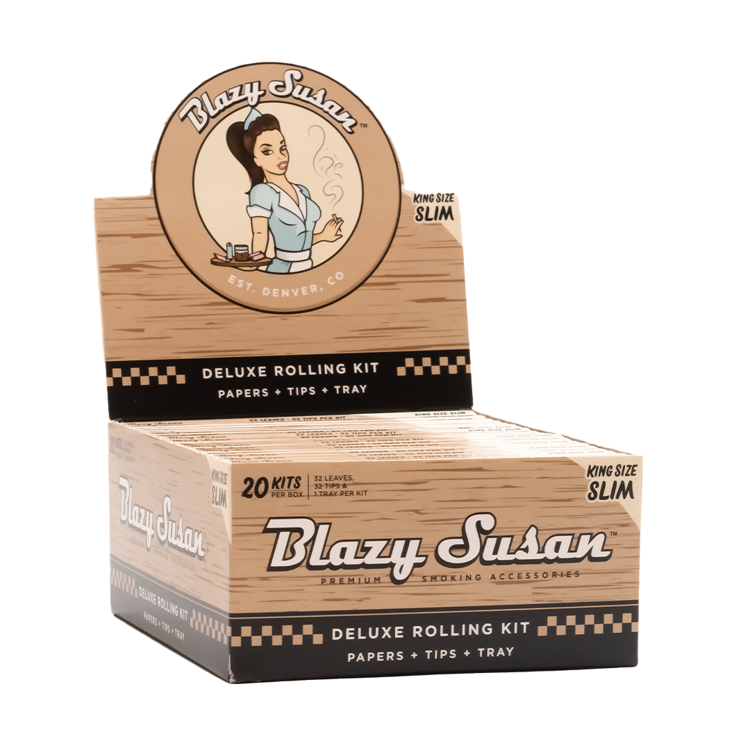 A front view of the Unbleached Rolling Papers package displays a retro-style logo and "Deluxe Kit" text over a neutral background. A front view of the Unbleached Rolling Papers package displays a retro-style logo and "Deluxe Kit" text over a neutral background.
