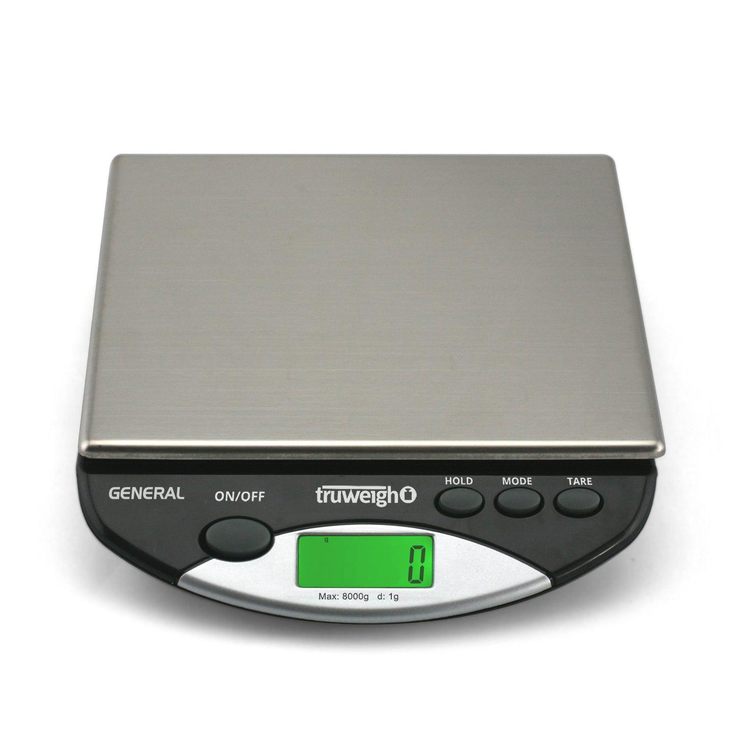 The General Compact Bench Scale is shown in a close-up, top-down view with a digital display and multiple buttons. The General Compact Bench Scale is shown in a close-up, top-down view with a digital display and multiple buttons.
