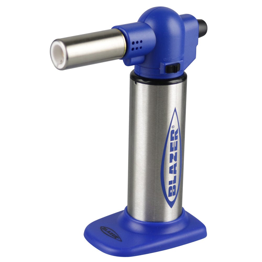 A side view of the Big Buddy Torch Lighter with a blue handle and metallic nozzle, resting on a dark surface. A side view of the Big Buddy Torch Lighter with a blue handle and metallic nozzle, resting on a dark surface.