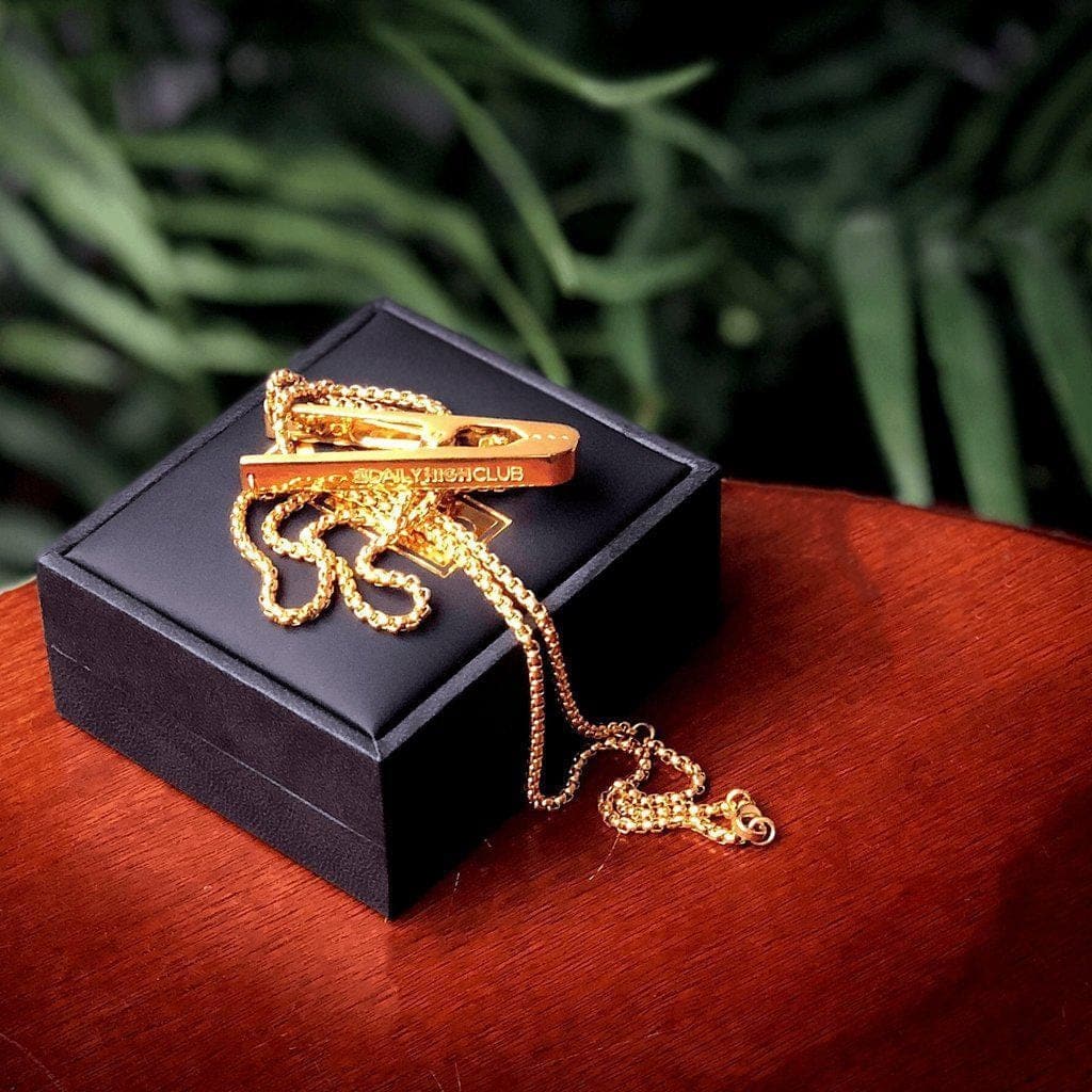 A close-up of the gold Roach Clip displayed on a black velvet surface. A close-up of the gold Roach Clip displayed on a black velvet surface.