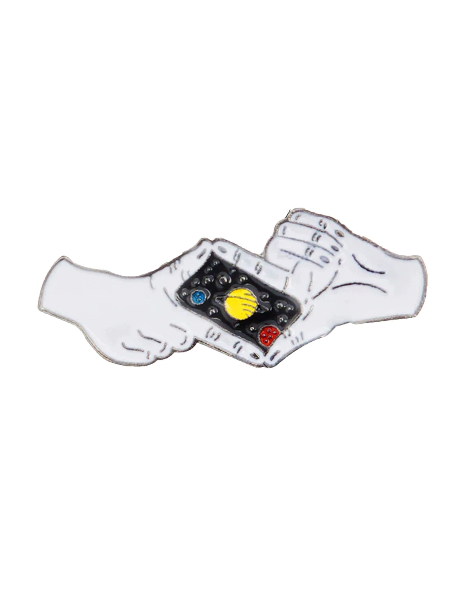 A close-up, slightly angled view of the Picture The Universe Enamel Pin held between two fingers against a plain white background. A close-up, slightly angled view of the Picture The Universe Enamel Pin held between two fingers against a plain white background.