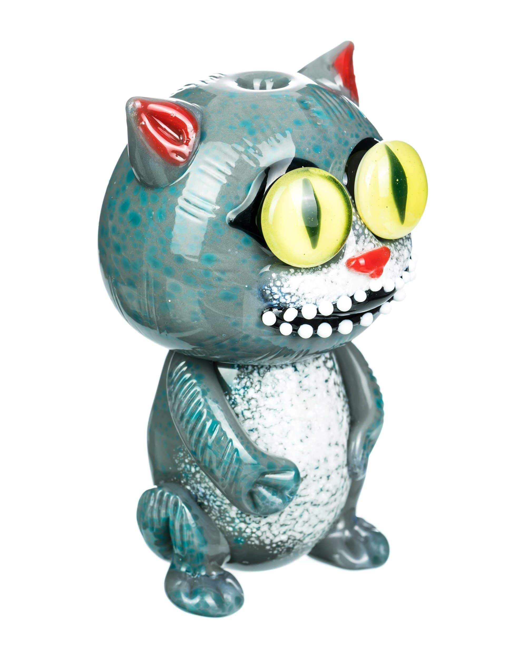 A front view of the “Galacticat” Hand Pipe, a sculpted ceramic piece resembling a cat’s head in shades of blue and green. A front view of the “Galacticat” Hand Pipe, a sculpted ceramic piece resembling a cat’s head in shades of blue and green.