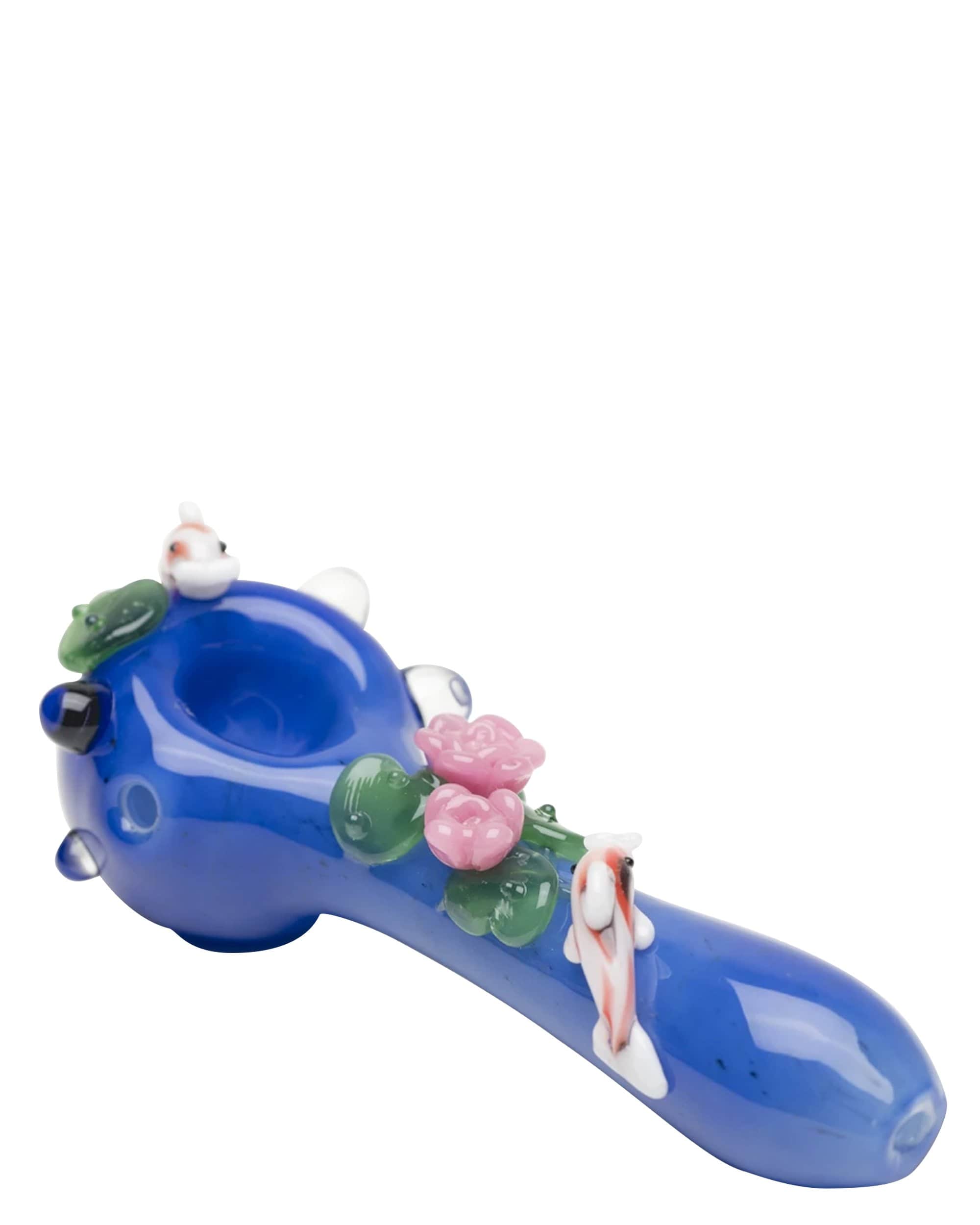 A side view of the Koi Pond Mini Spoon Pipe, showcasing its sculpted blue form with detailed koi fish and floral accents. A side view of the Koi Pond Mini Spoon Pipe, showcasing its sculpted blue form with detailed koi fish and floral accents.