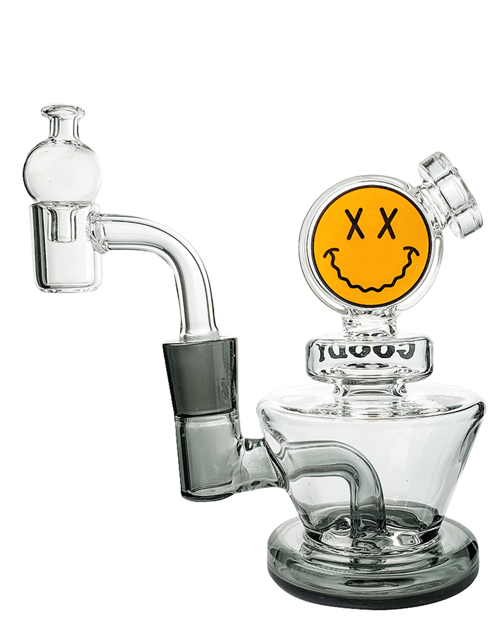 A three-quarter view of the Big Face Mini Rig 4-Piece Kit, featuring a smiling face design on clear glass. A three-quarter view of the Big Face Mini Rig 4-Piece Kit, featuring a smiling face design on clear glass.