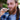 Close-up of a bearded man holding the Cipher NOVA | Stainless Steel - V2 metal vaporizer to his lips with a braided ponytail and blurred greenery background