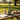 Park-side picnic scene showing the Jane West Limited Edition Sidekick by GEAR Premium green glass sidecar bong centered on a wooden table.