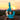 Handheld against a soft sunset, the Ooze Echo 4-in-1 Silicone Bong in rasta-colored teal-blue is shown in three-quarter view highlighting its curved clear neck and textured silicone body.
