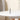 Center close-up of the ONGROK USA Taster Bat - Aluminum One-Hitter standing upright on a white round table against a soft beige background with a potted plant edge.