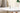 Center close-up of the ONGROK USA Taster Bat - Aluminum One-Hitter standing upright on a white round table against a soft beige background with a potted plant edge.