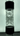 Vertical close-up of the Prism Flower Power Beaker Double Stack showing the clear glass double-chamber percolator and black banded connectors against a soft backlit background