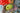A hand holds the Lemon Pipe, with its smooth, rounded form highlighted against a blurred, colorful floral background.