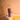 Center-framed, top-down view of a muted mauve Staze STAZE PRESERVE bottle standing on draped fabric with soft dried flower shadows behind.