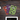 Top-down view of three colorful ONGROK Color-Coded Mylar Bags fanned on a dark wood surface showing bold green, purple, and orange circular patterns.