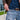 A close-up, side view shows the Premium Storage Tube peeking out of a denim pocket, contrasting with the leather belt.